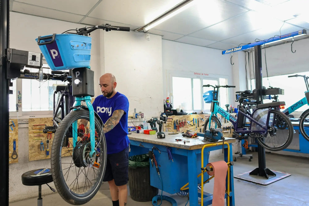 Technician servicing an electric bicycle in a professional repair workshop with tools